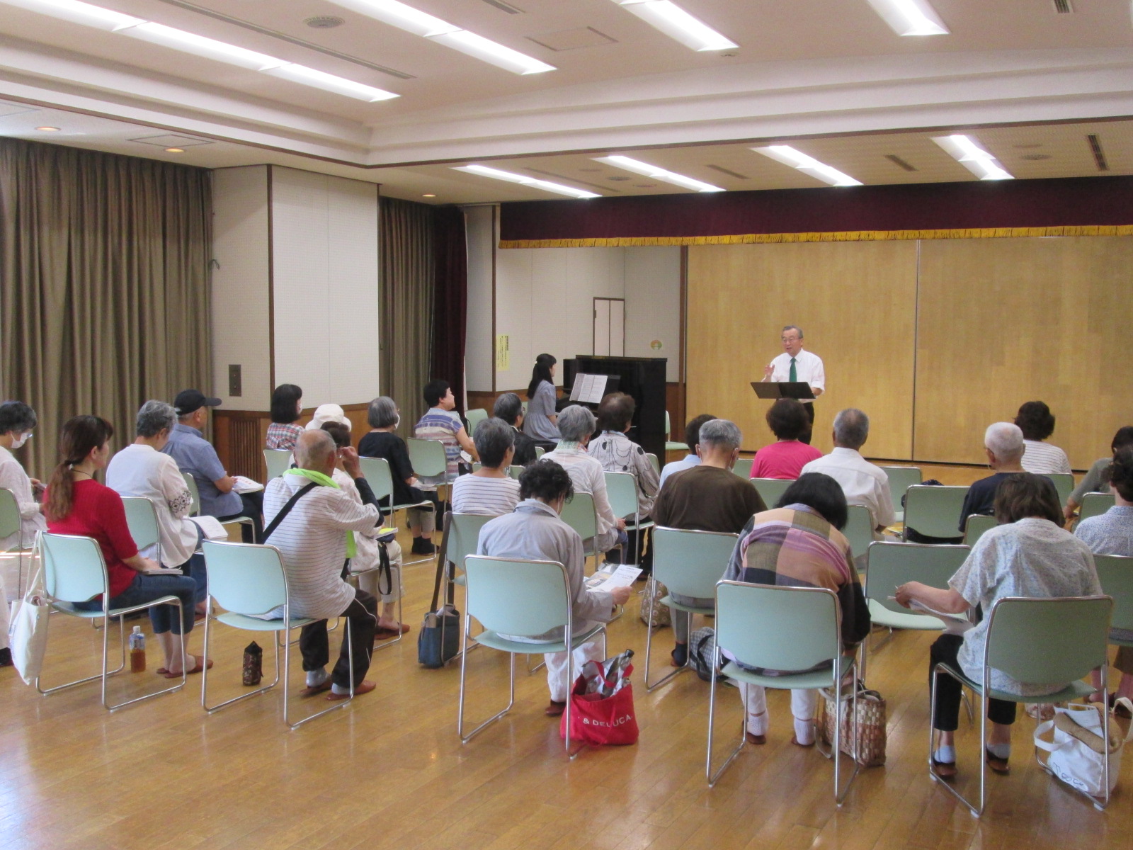 多目的ホールにて椅子に座って講演者の話を静かに聞いている参加者たちの様子を写した写真