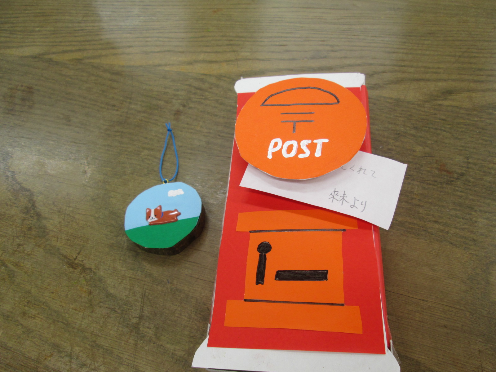 手作りの郵便ポストと、子どもが描いたと思われるカラフルな絵が飾られている様子を写した写真
