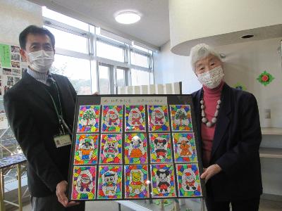 「10周年記念 渋沢ほっとサロン」と書かれた額縁を、マスクをつけた男女が持ち、中には色鮮やかなクリスマスやキャラクターの絵が複数並べられている写真