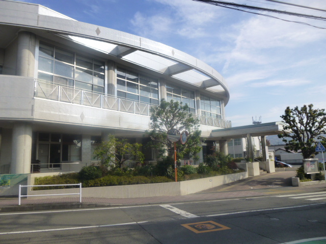 白いタイル張りのモダンな建物で、曲線的な庇と大きな窓が特徴の秦野市立本町公民館の外観写真