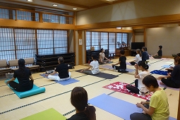 畳の部屋で複数の人がヨガマットを敷いて座り、瞑想しているヨガ教室の写真