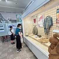 和装や旗などの展示物が入ったガラスケースを、親子が興味深そうに眺めている写真