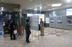 古い白黒写真や説明文がパネルに展示してあり、来場者が鑑賞している様子の写真