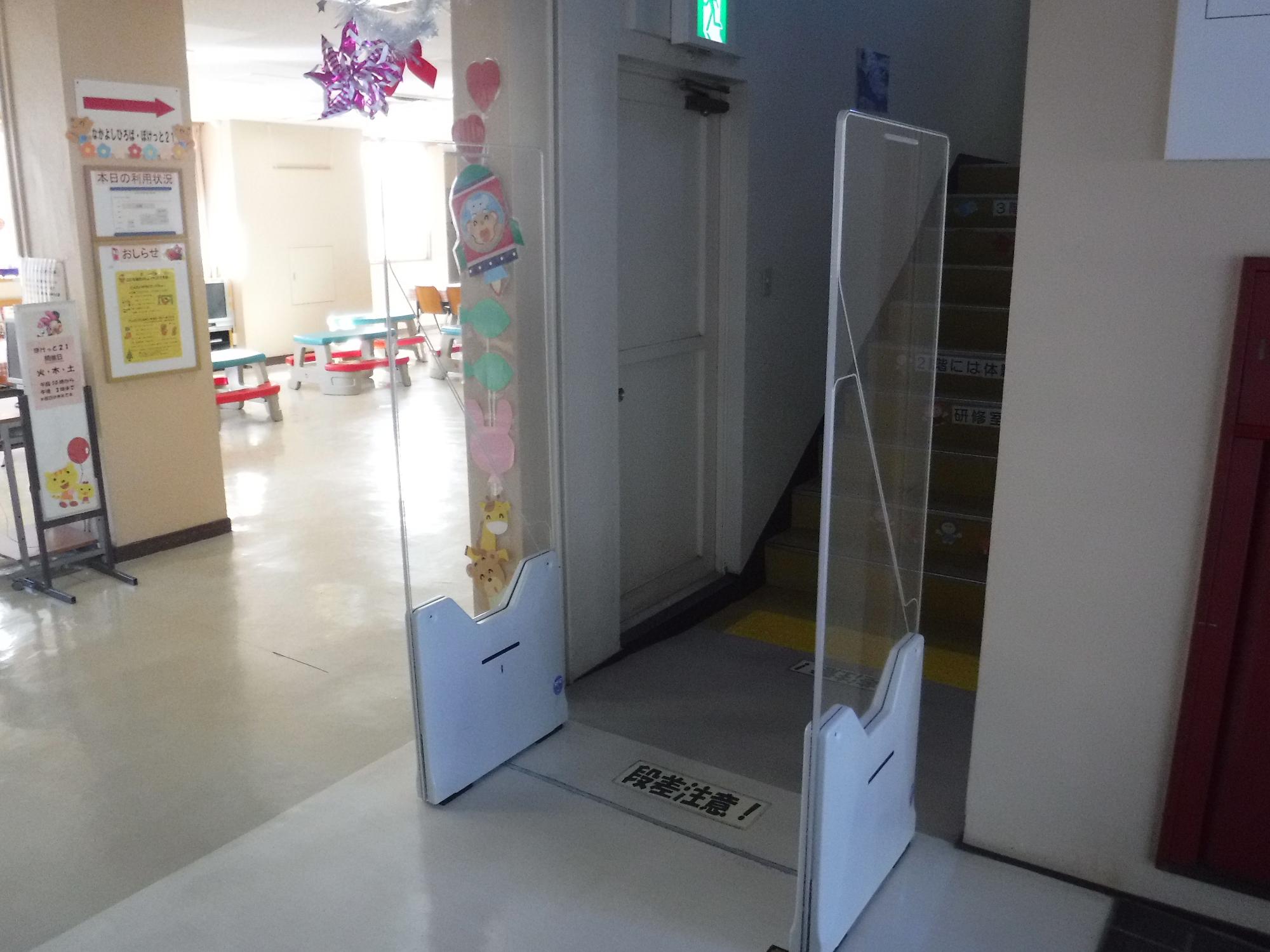 透明なアクリル板でできた持ち出し防止用ICゲートが、階段の入り口前に設置された写真