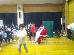 クリスマス会でサンタさんにプレゼントをもらう子供たちの写真