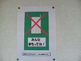 中央に携帯電話に赤いばつが引かれたイラストがあり、周囲に「みんな まもってね！」と書かれた貼り紙が壁に貼られている写真