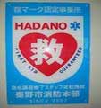 水色の背景に、赤色の大きなハートマークが描かれ、その中に白色で「救」という漢字が強調され、上部には「HADANO」と「救マーク認定事業所」、下部には「秦野市消防本部」の文字が書かれた写真