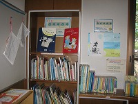 左側に絵本や児童書が並んだ本棚があり、右側の壁には賞状やポスターが貼られている室内の写真
