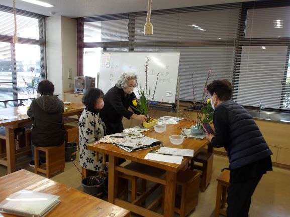 大きな机の上で講師が参加者2名に指導をしている