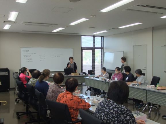 講師が前に立ち数名の大人の前で挨拶をしている