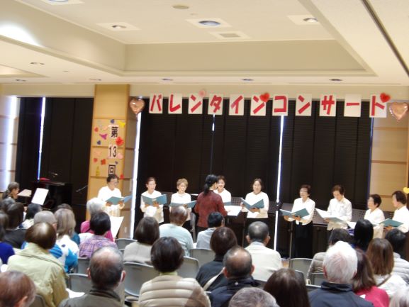 多目的ホールで観客の前でコーラスさざんのサークルが譜面を持ち歌っている