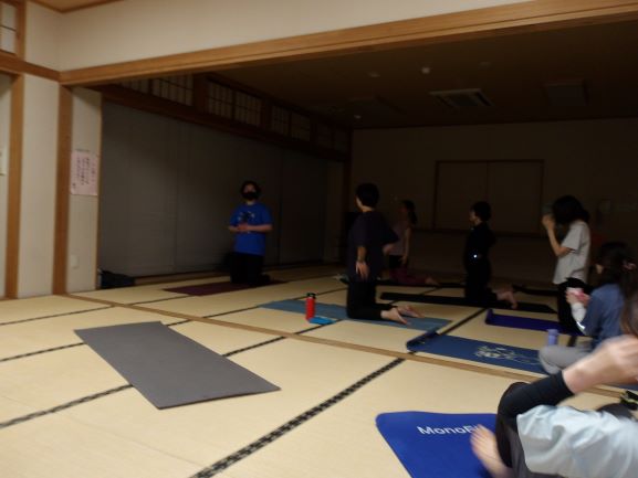 和室で数人の女性が薄暗い中ヨガのポーズをしている