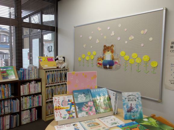 図書室の壁面に熊とウサギの絵と黄色の菜の花が切りえで貼ってある