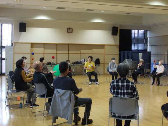 ホールで多数の人が椅子に座り講座を受けている