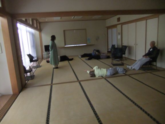 和室で女性の講師が立ち受講者はね転んでいる状態