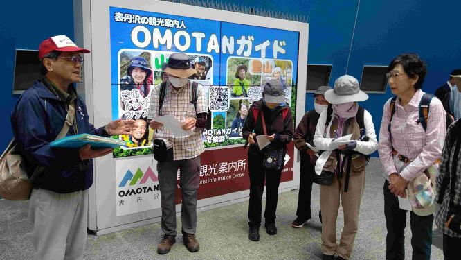 駅で集合している写真大人が5人駅の改札に立っている
