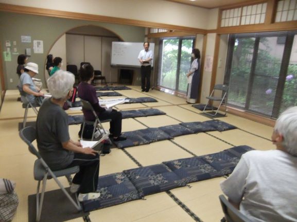 和室で数人の女性が椅子に座りその前に座布団を4枚敷いてあるところで話を聞いていている写真
