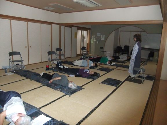 和室で座布団を敷いたうえで情勢数人が体をひねっている