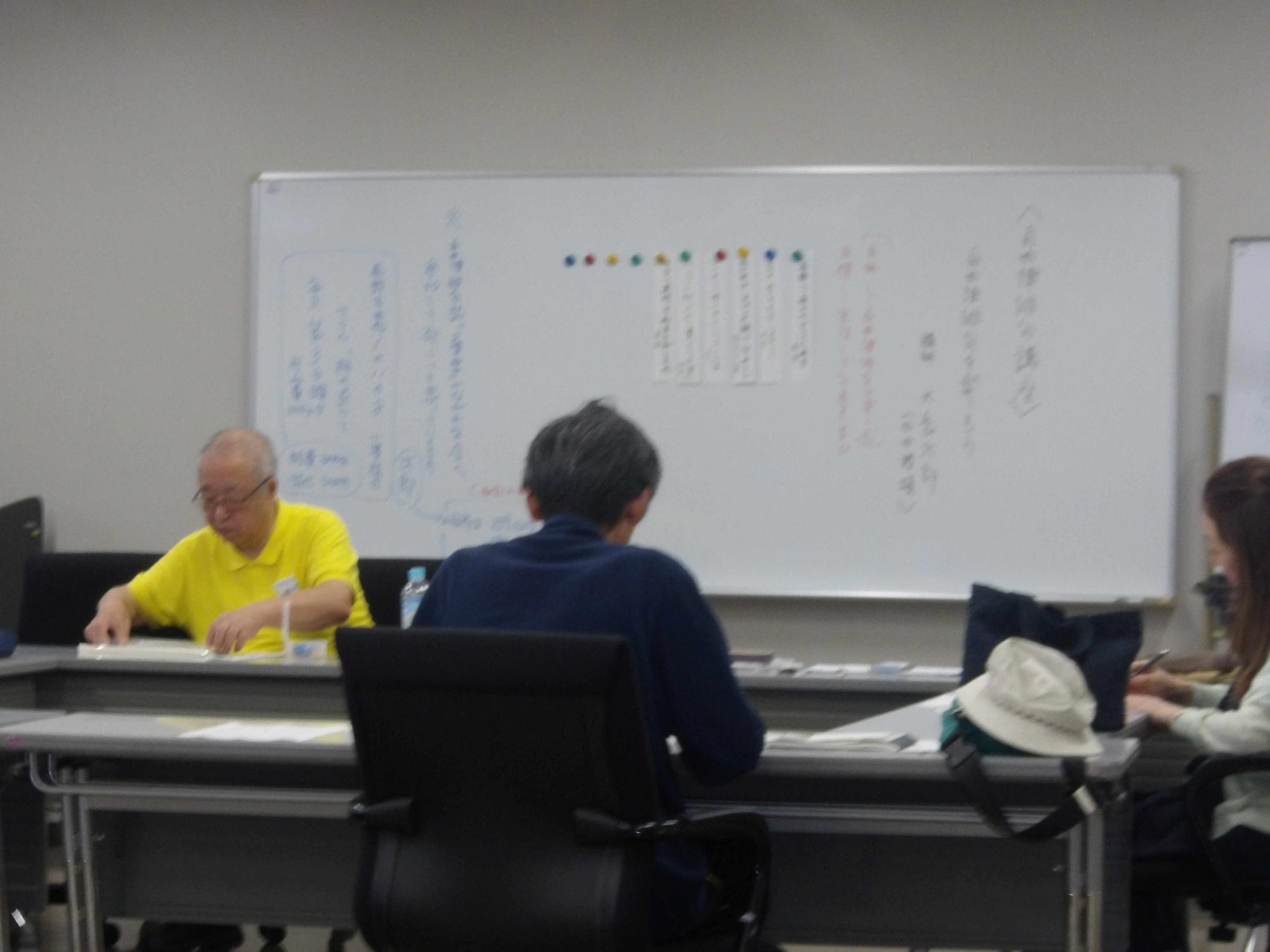ホワイトボードの前に大人が3人椅子に座り講座を受けている