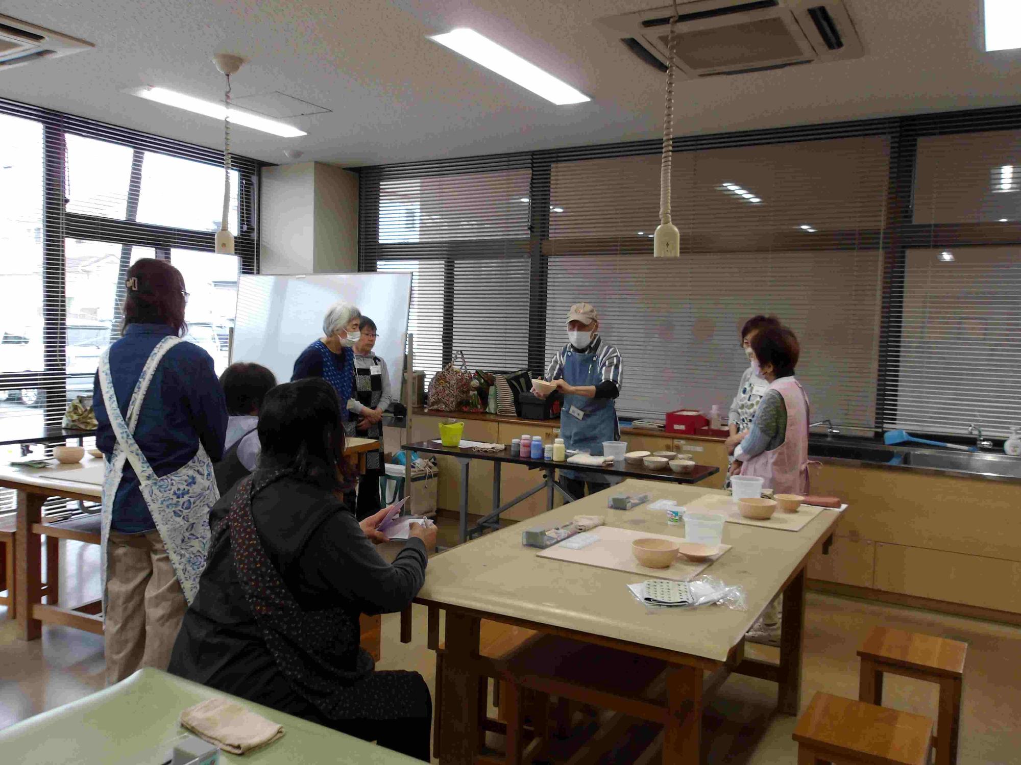 男性が前に立ち数名の講座参加者に説明をしている