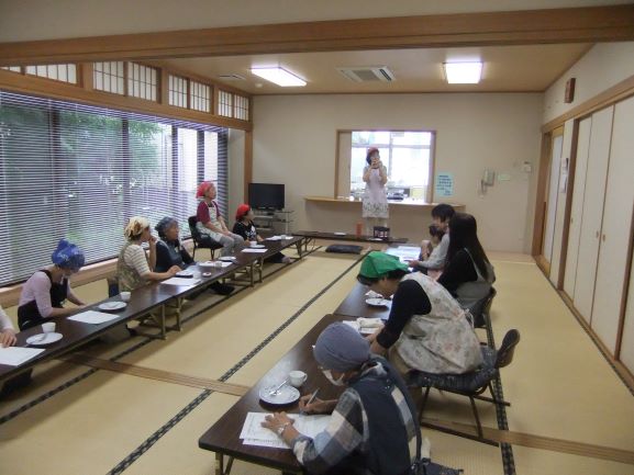 和室で女性がオカリナ演奏してるのを大人の女性数名が座って聞いている