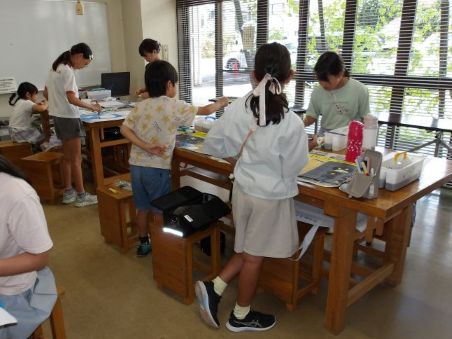 子どもたちが大きな机で絵を描いている
