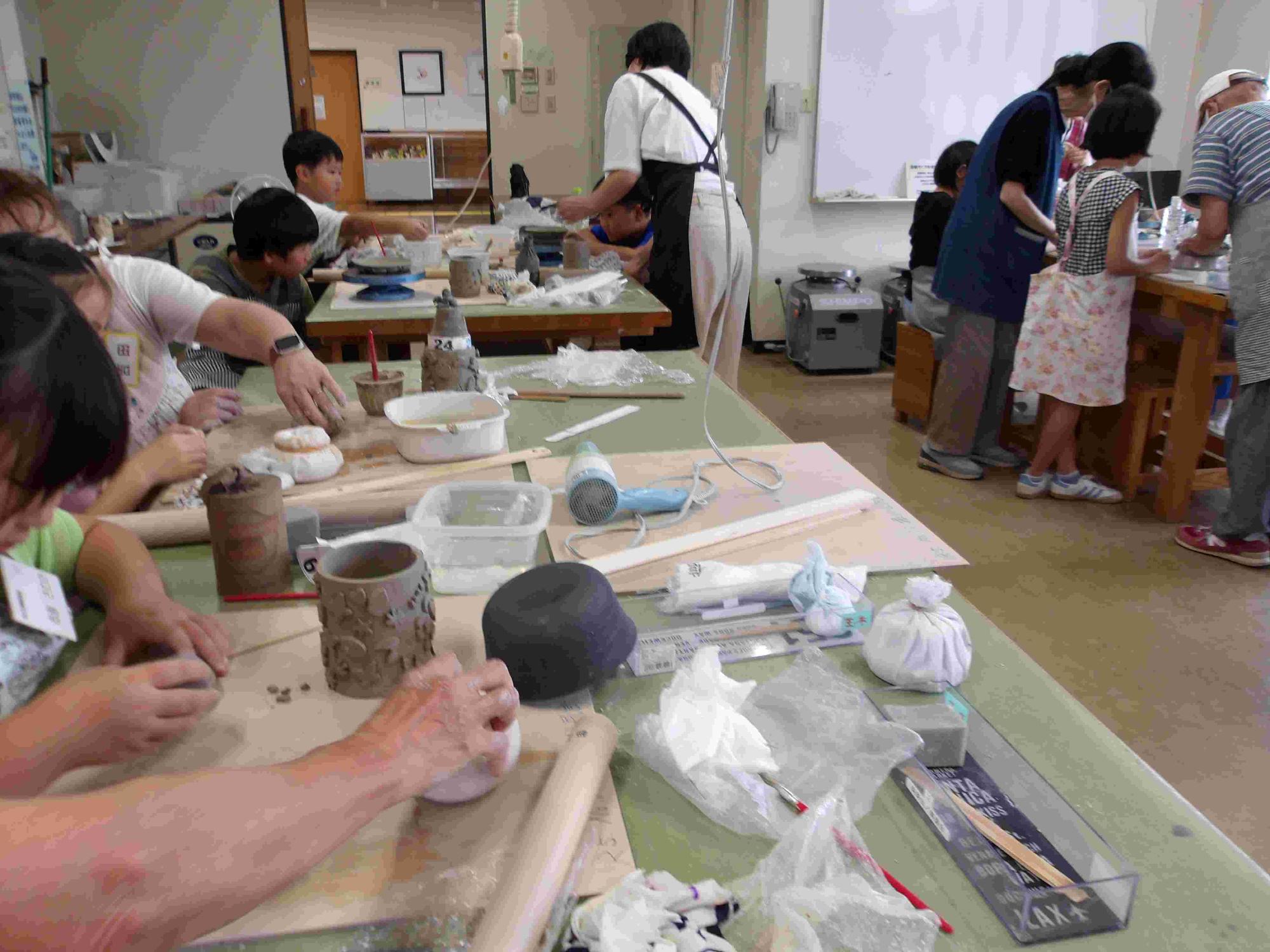 子どもたちが大きな机の上で粘土を練っている