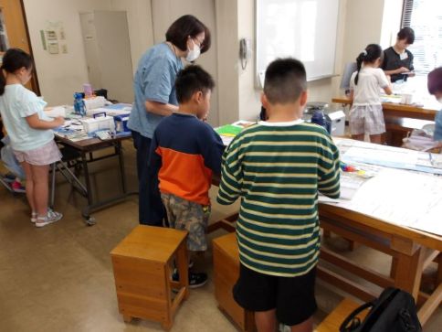 子どもたちが絵を描いているところに講師が指導している