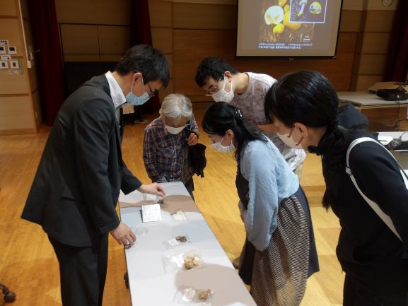 机の上にキノコの標本を大人が数名で見ている