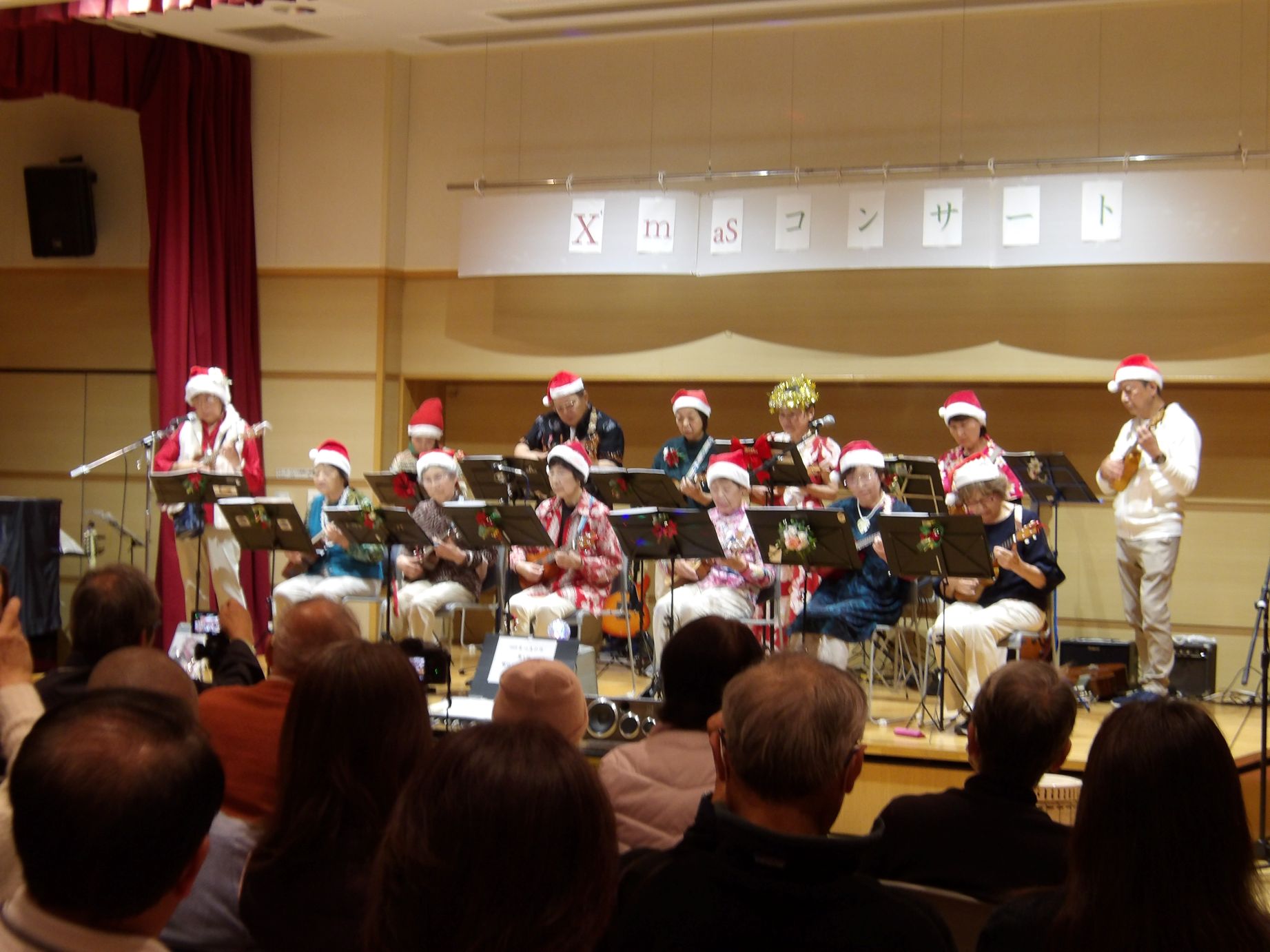 クリスマスコンサートでパーリーシェルズ演奏サンタの赤い帽子をかぶりウクレレの演奏をしている
