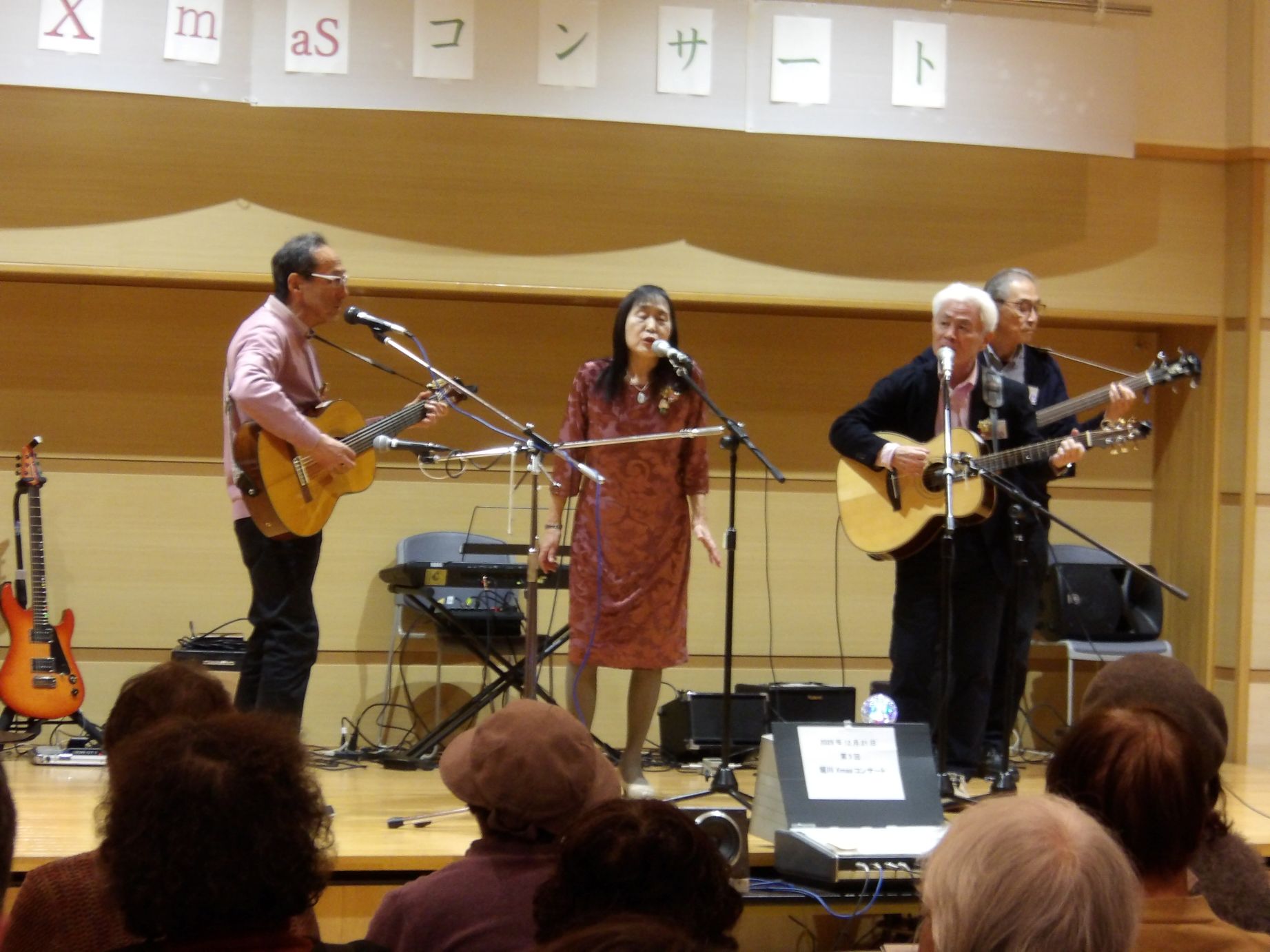 Wisteria演奏クリスマスコンサートで3人で舞台にいてギターを弾いている人と歌を歌っている人がいる