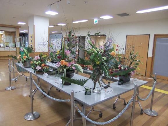ロビーの中央に長机並べその上にフラワーアレジメントの作品を多く展示してある