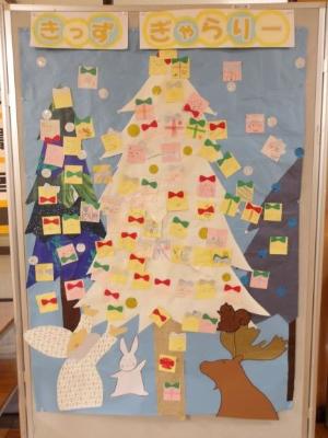 水色ベースの模造紙にクリスマスツリーの絵がありそこに飾りのプレゼントが描かれた「きっずぎゃらりー」の掲示物の写真