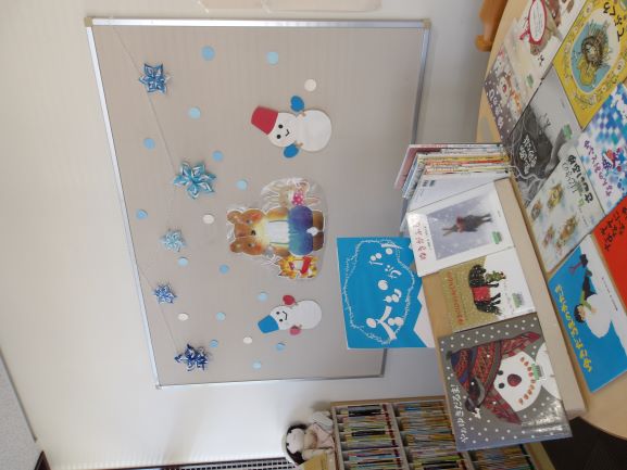 図書室の奥の壁面に雪だるまと熊の絵が貼ってありその前に絵本が置いてある