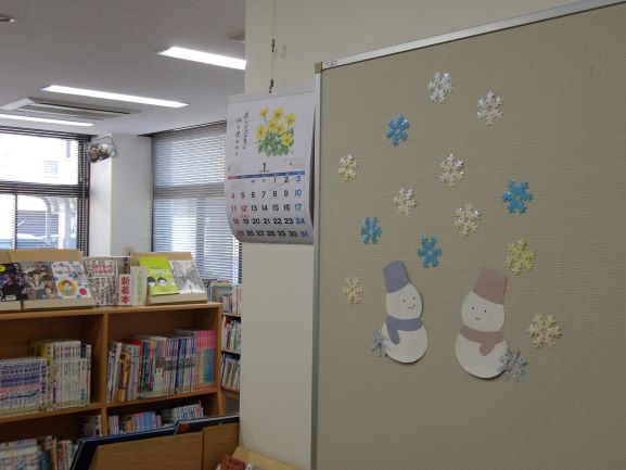 図書室の壁面に雪の結晶の切り絵と雪だるまが2体の絵が貼ってある