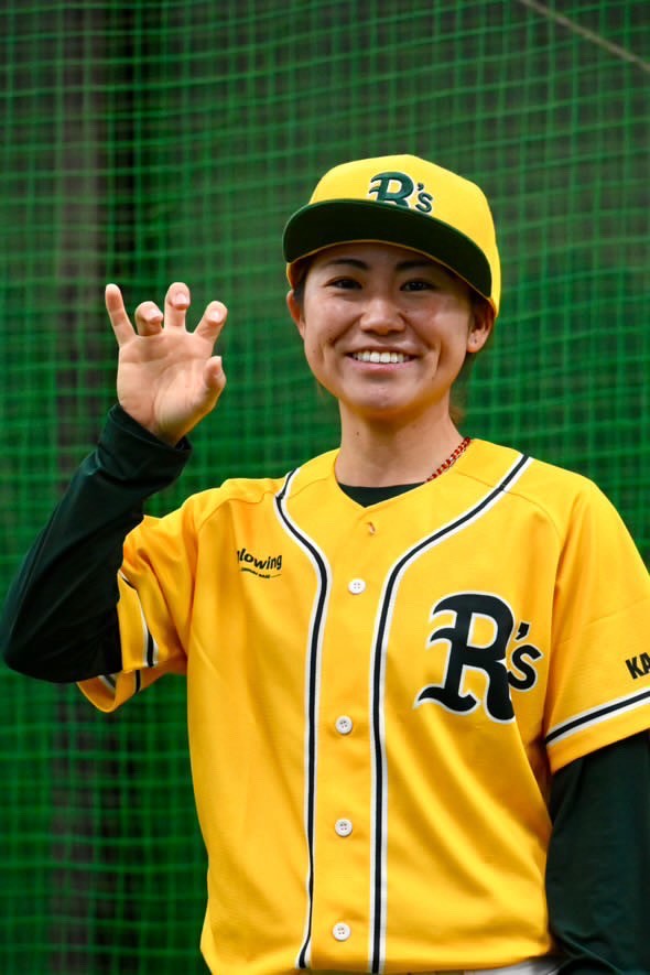 黄色いユニフォームとキャップを着用した田上亜純選手が、黒い長袖インナーの上にユニフォームを着て、笑顔でOKサインをしている屋内での上半身の写真