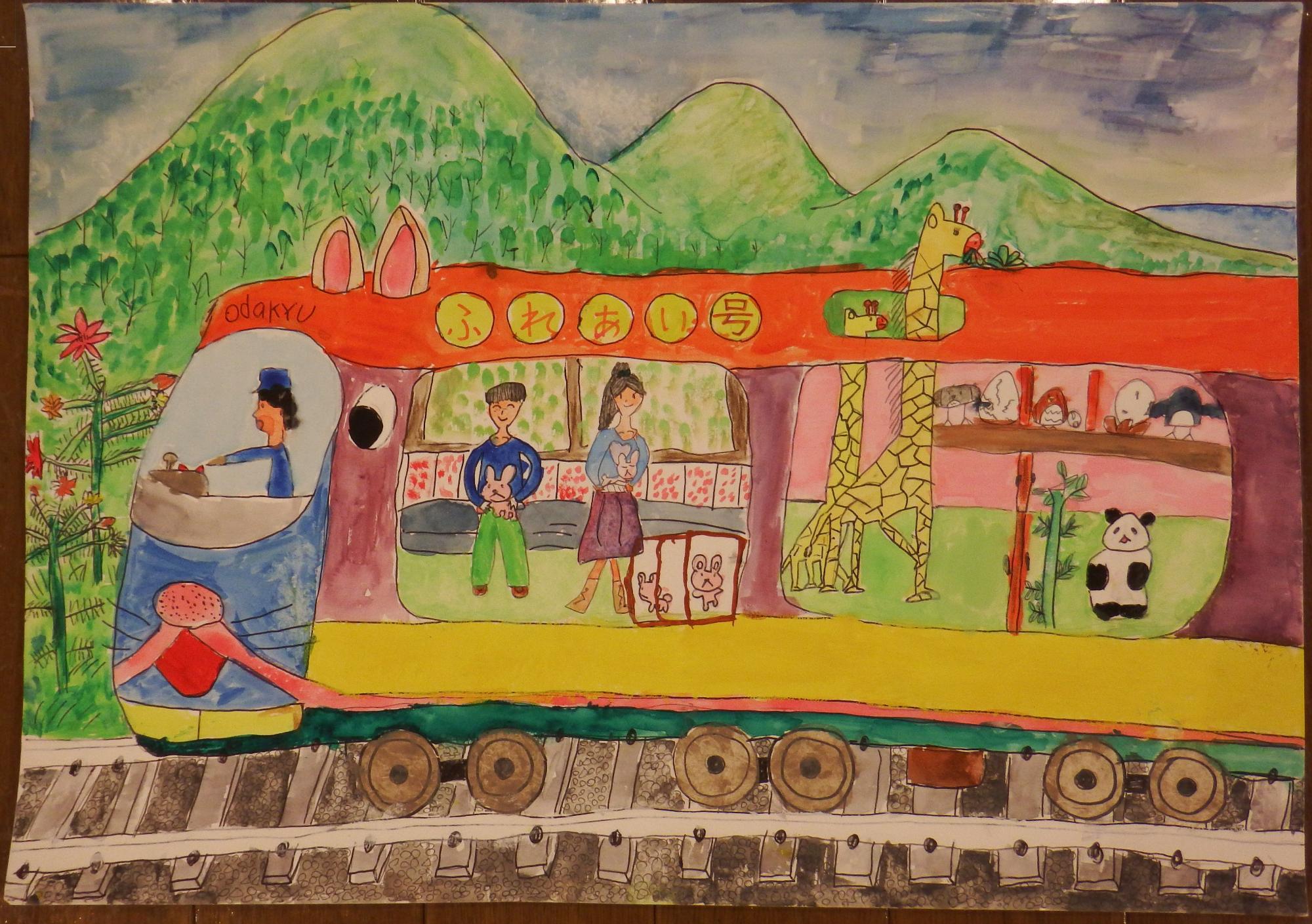 緑豊かな山々が広がる背景に、動物を抱っこしている男性と女性の乗客やキリンやパンダなどの動物たちが乗車しており、動物の耳や、猫の様な髭や鼻、口が描かれたオレンジや黄色などのカラフルな車体横に「ふれあい号」と書かれた電車が線路の上を走っている様子が描かれている、子供らしいタッチの絵画の小田急電鉄賞受賞作品の写真