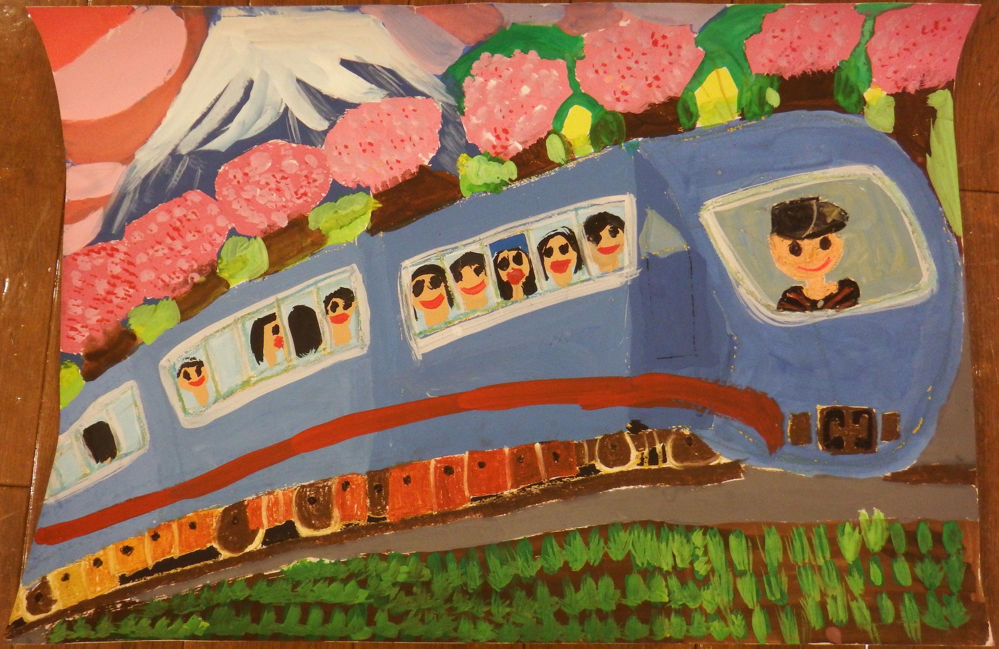 富士山とピンク色の花畑を背景に赤いラインの入った青色の電車の窓から笑顔の乗客が顔を覗かせ、運転手も微笑んでいる電車が走っている様子が描かれた入選受賞作品の写真