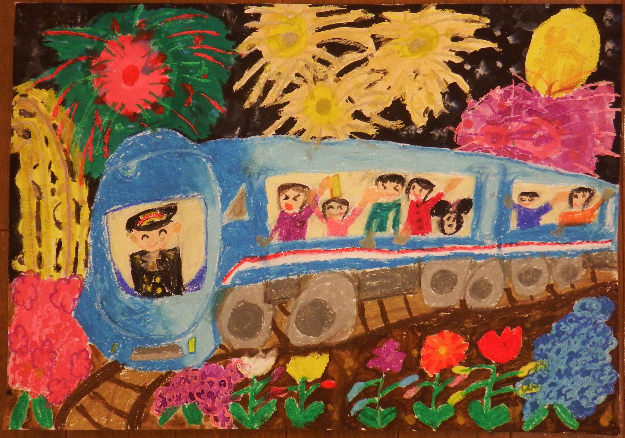 真っ暗な空には花火が打ち上げられ、周囲には色とりどりの花々が咲き誇った線路の上を青い電車が走り、窓から楽しそうな乗客が手を振っている様子が明るい色調で描かれた絵画の入選受賞作品の写真