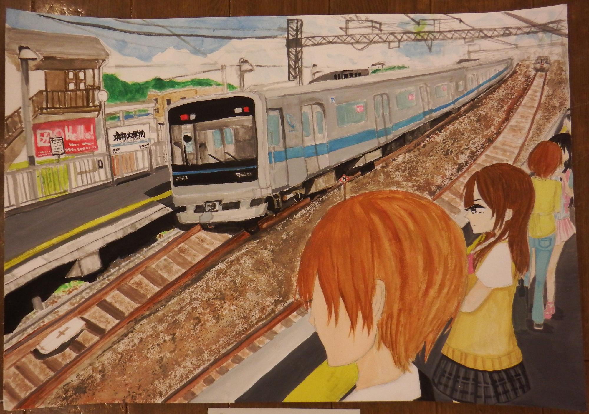 イラストタッチで描かれた駅のホームで、一人の男性が線路を眺め、その奥では複数の制服姿の女子生徒や2人組の女性が電車が来るのを待っており、奥のホームの線路には青いラインの入ったグレー色の電車が停車している風景を描写した入選受賞作品の写真