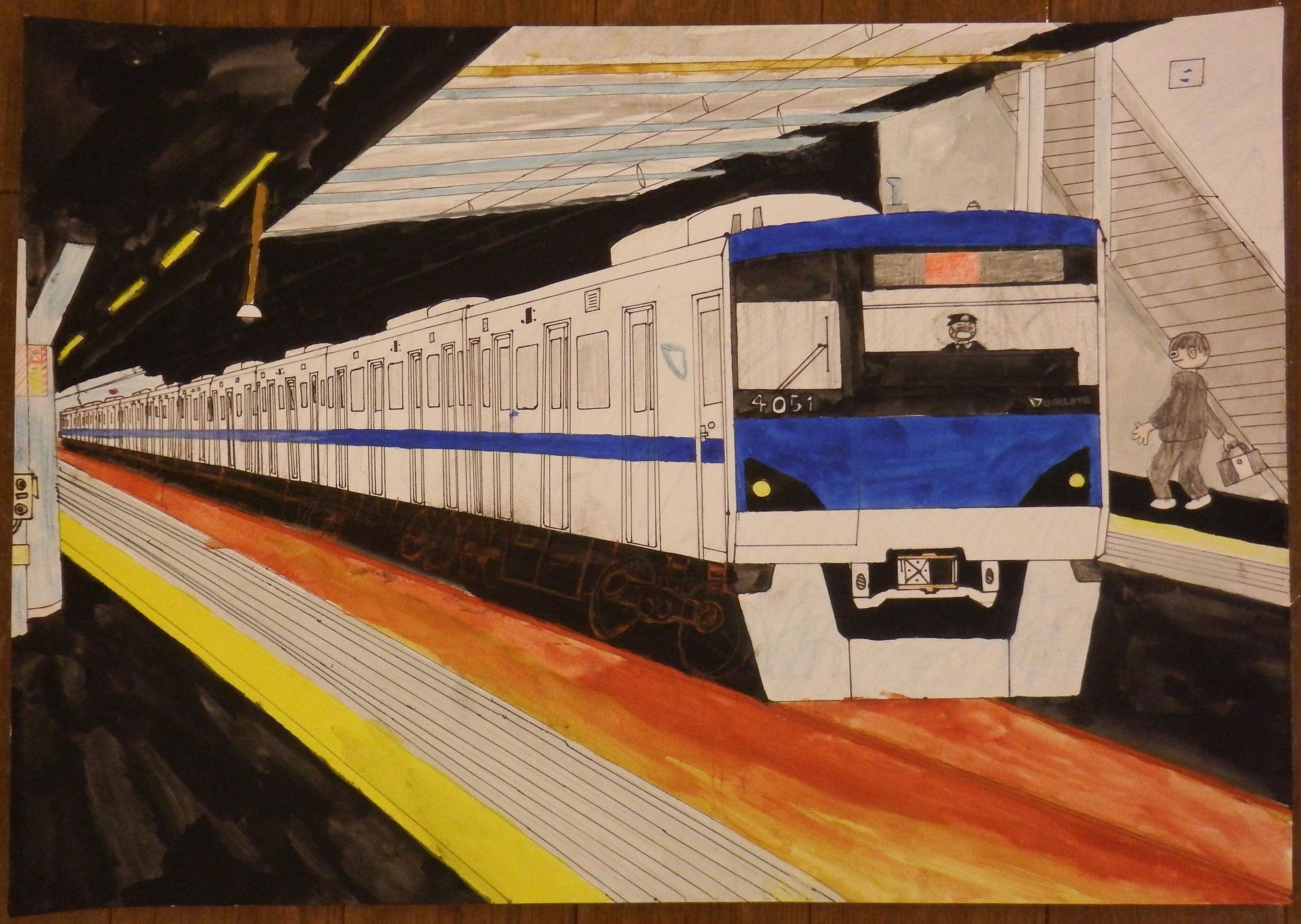 奥の改札へ向かう人物や階段と、駅のホームに停車している白と青のラインが入った電車を遠近法を用いて反対側のホームから描いた入選受賞作品の写真