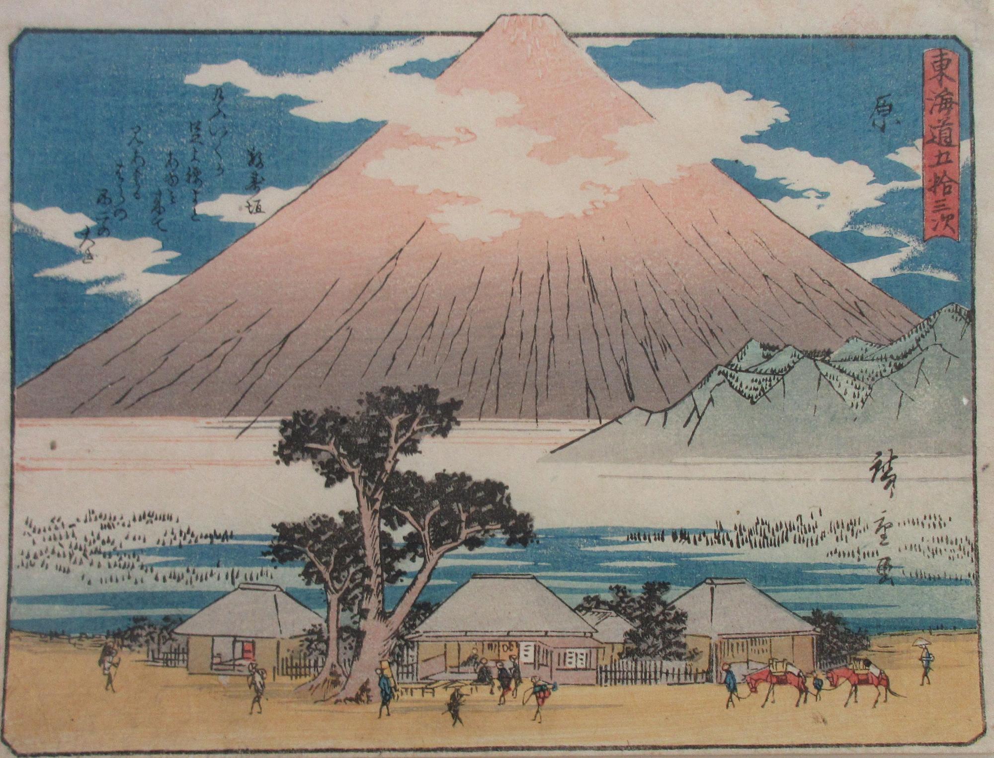 周囲に雲が浮かんでいる大きな富士山を背景に、瓦葺きの家が数軒建ち並び、その間を多くの人々や馬が行き交う江戸時代の風景を描いた浮世絵