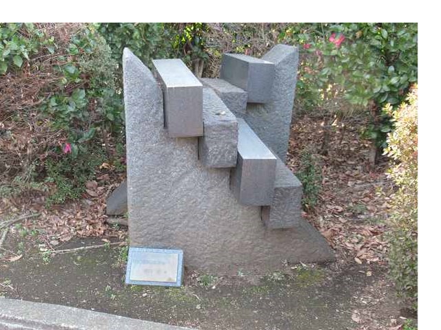 複数の角ばった直方体の石が、大きな岩に組み合わされ階段のように配置された、抽象的な石造りの屋外彫刻の写真