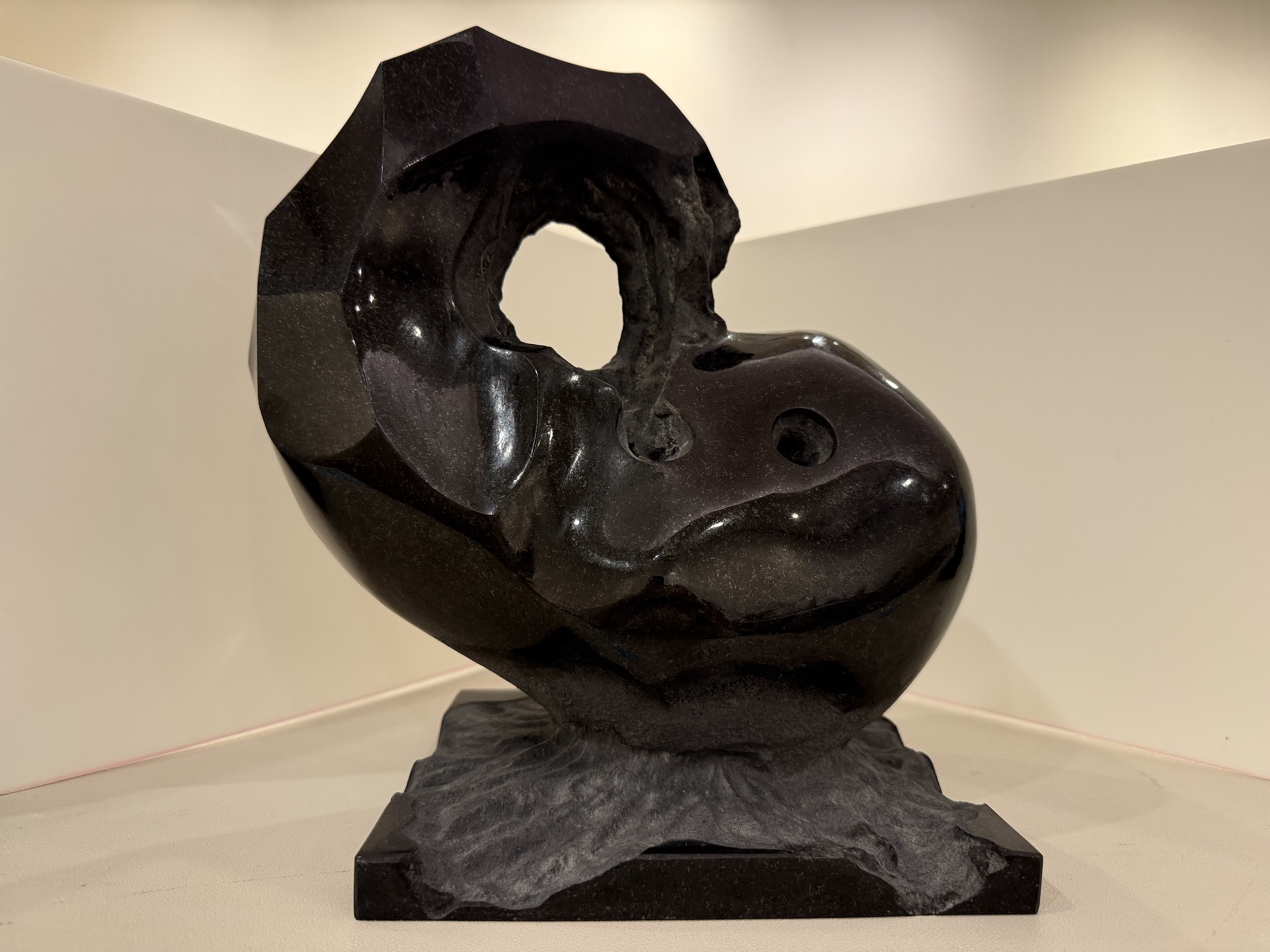 岩のようにざらついた質感の台座と対照的に、勾玉の様な抽象的な形で大きな穴が空いた磨かれた黒い石で作られた彫刻の佳作受賞作品の写真