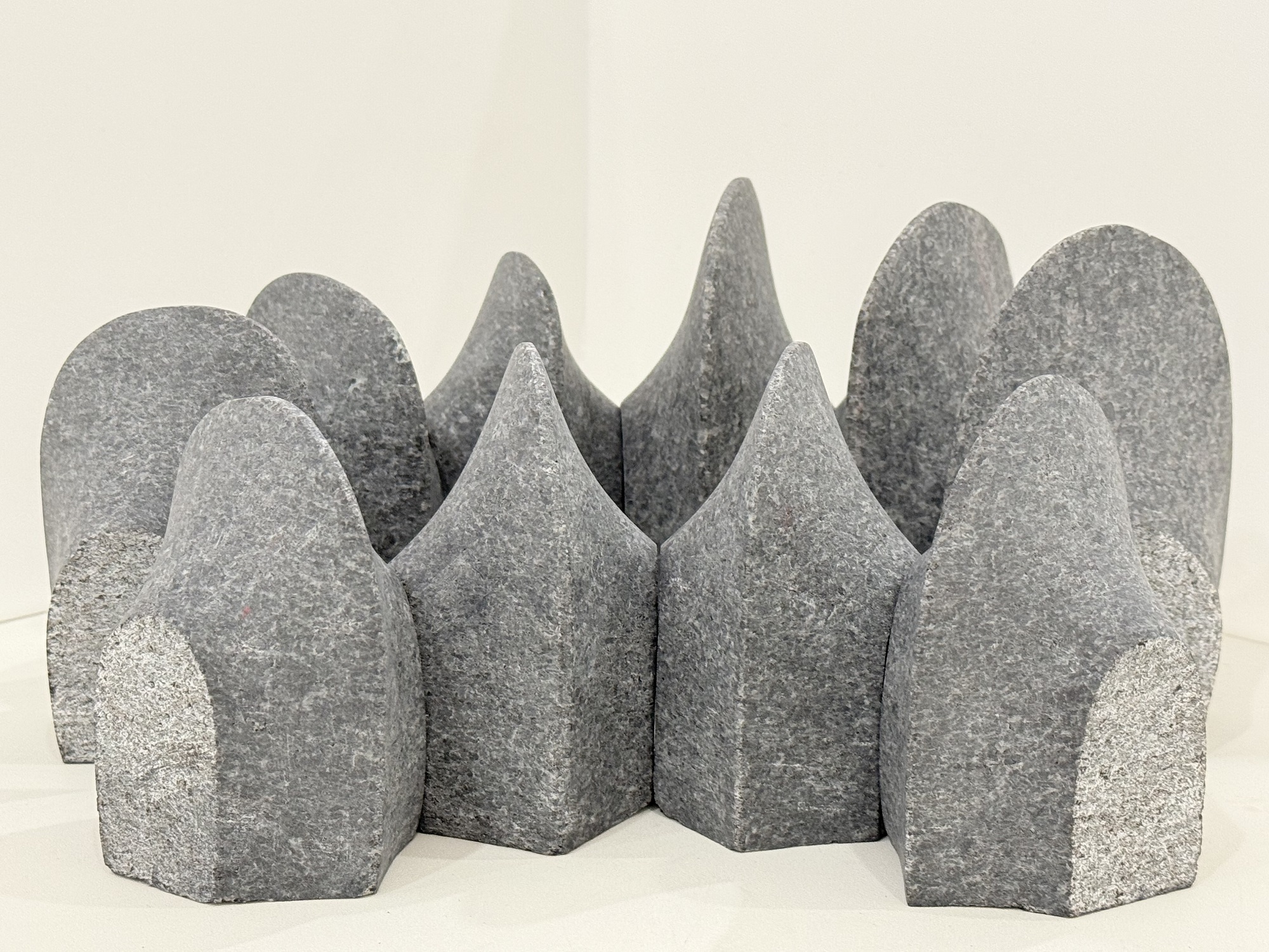 丸みを帯びた形状と尖った形状の、表面がざらざらした灰色の石が、複数集まって山脈のように配置されている現代彫刻の佳作受賞作品の写真