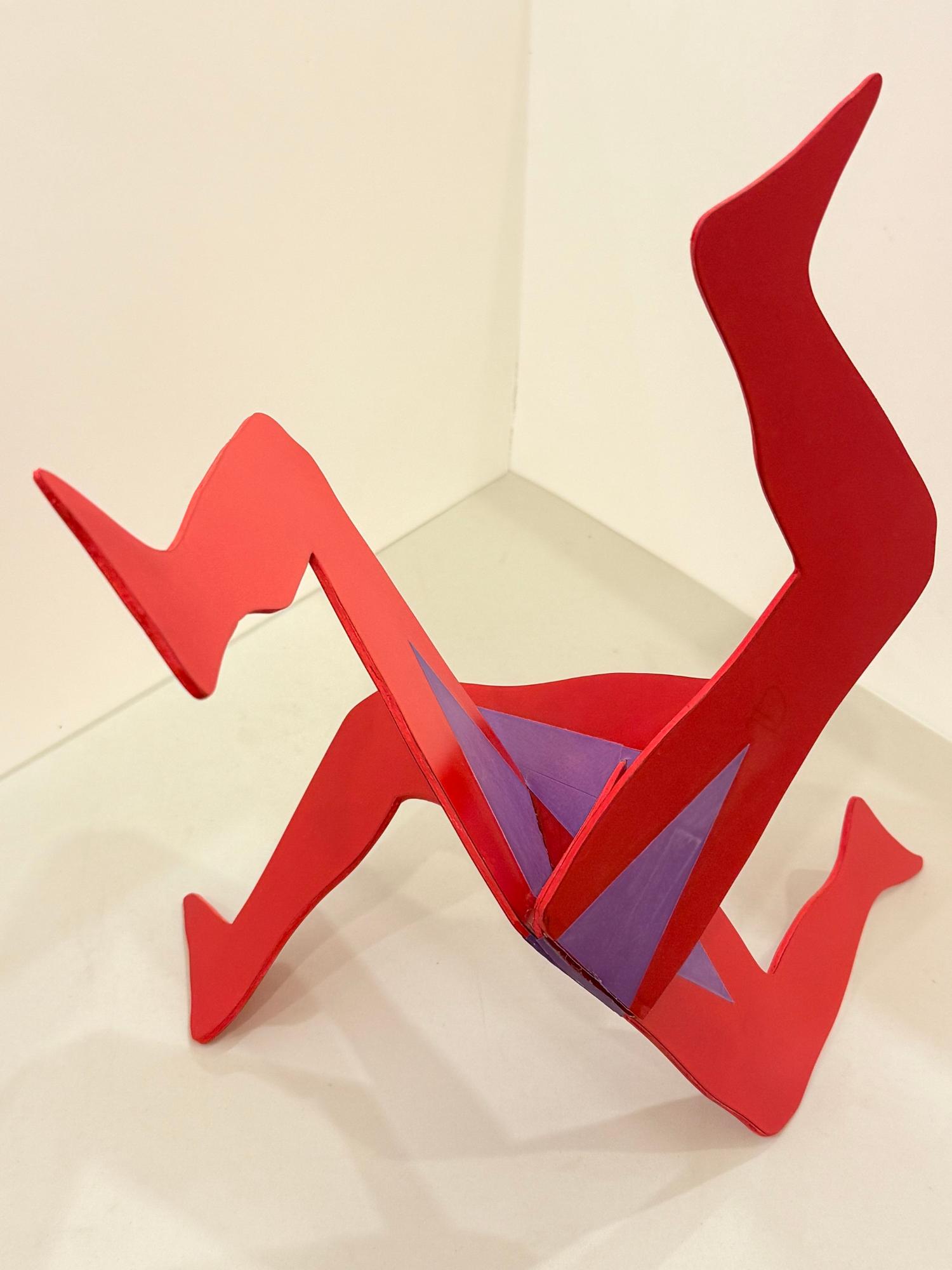 赤と紫の金属板を組み合わせた、何本もの足が絡み合うような複雑な形状で、躍動感のある動きを表現した抽象彫刻の佳作受賞作品の写真