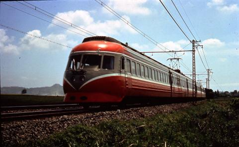 田んぼの中の線路を赤い先頭車両と白い側面が特徴的な流線型の電車が走っている小田急ロマンスカー3000形の写真