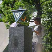 黒い御影石の台座の上にある逆三角形の形をしたモニュメントに、少年が火のついたトーチで火を灯そうとしている様子の写真