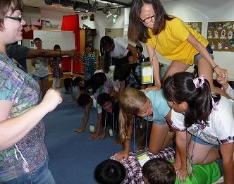 室内で複数の学生が手足をついて四つん這いになった人の背中に次の人が乗りピラミッド型を作るレクリエーションを行っている様子の写真