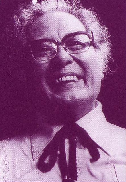 白いYシャツとループタイを身につけ、眼鏡をかけた宮永岳彦が、歯を見せて楽しそうに笑っている白黒のポートレート写真